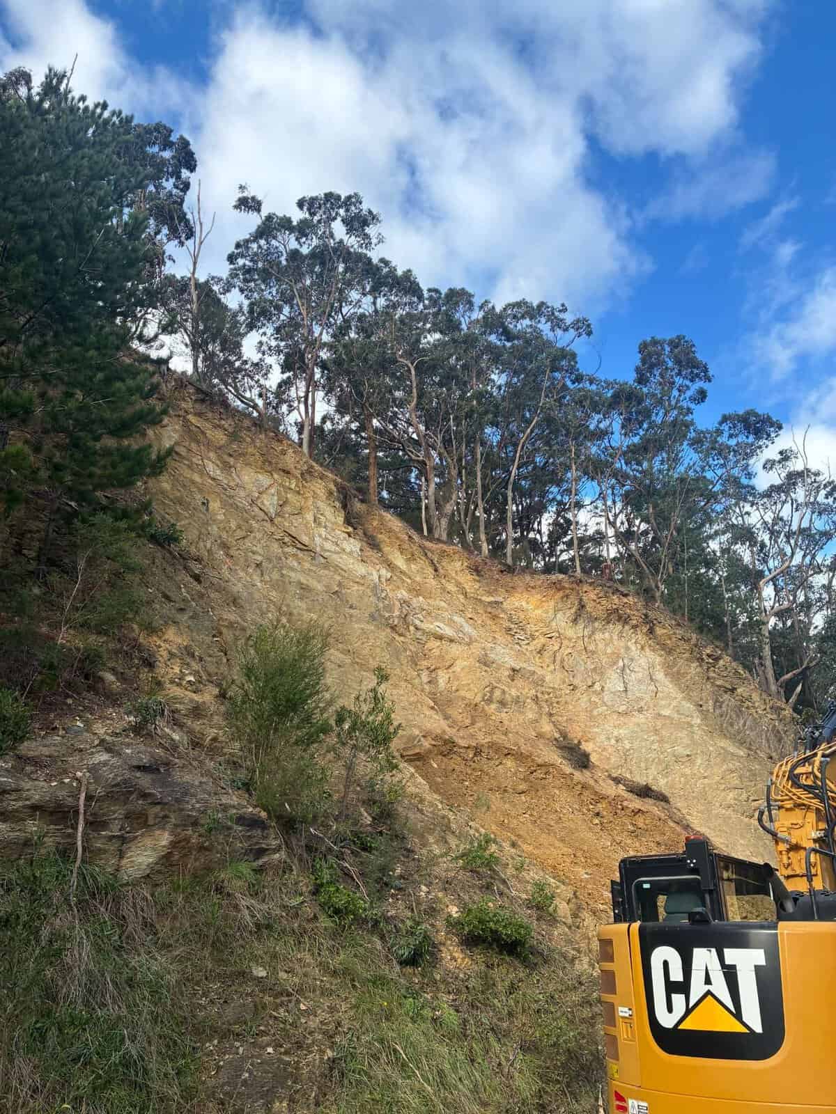 Excavator cutting a rock batter