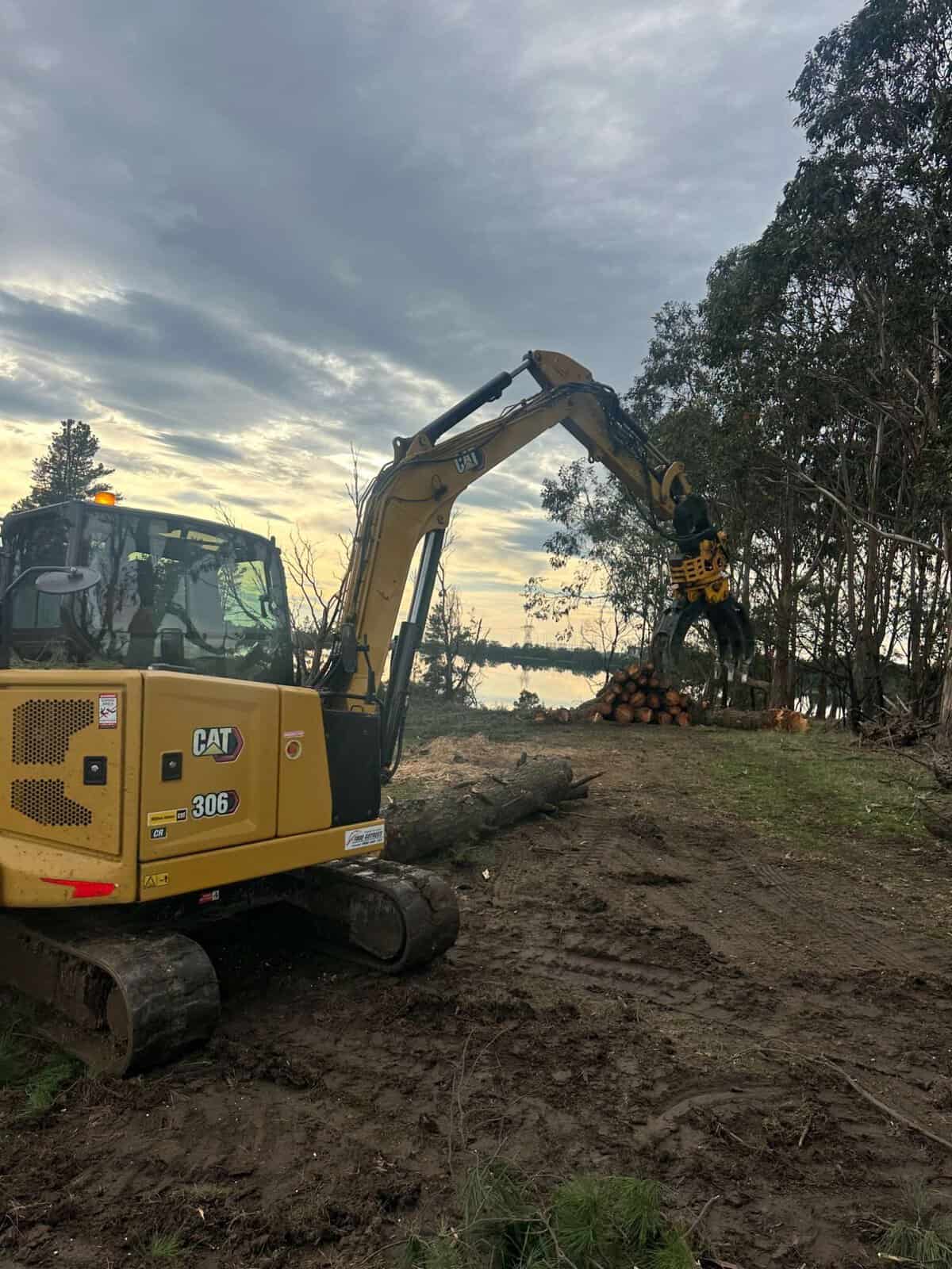 Land clearing excavator dusk logs